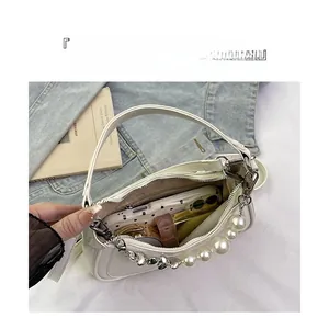 Detail view of white pearl handbag interior storing phone, lipstick and compact powder