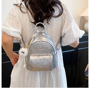 Close-up of silver floral mini backpack with a plush monster charm on the side
