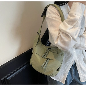 Close-up of sage green nylon crescent bag with woven zipper pull and plastic buckle