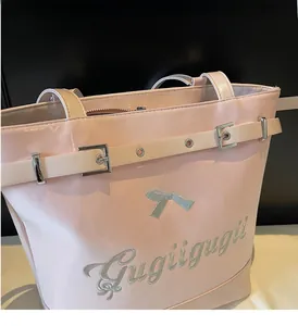 Détail du sac cabas en cuir verni rose avec logo argenté et boucle métallique décorative