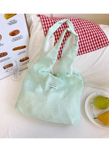 Close-up of light green floral canvas tote bag with Korean label in a cozy setting