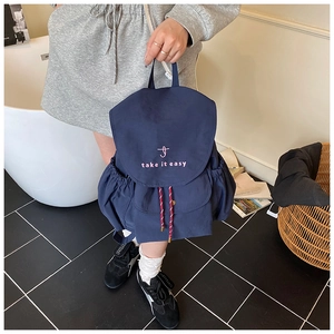 Détail d'un sac à dos bleu marine imperméable avec broderie rose et cordon rouge