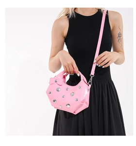 Détail du sac bandoulière rose brillant avec rivets argentés et nœud décoratif