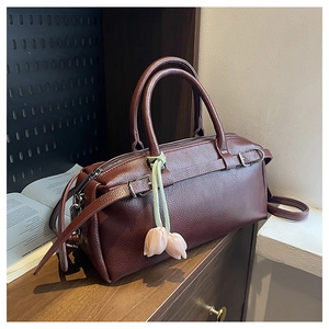 Close-up of wine red litchi texture boston bag with elegant tulip pendant and metal zipper