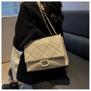 Close-up of beige quilted crossbody bag with gold chain strap and turn-lock closure