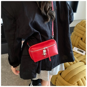 Close-up of red mini crossbody box bag with cute silver robot charm on black suit