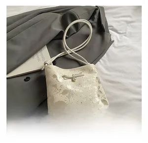 Close-up of cream bow shoulder bag with butterfly print and elegant pearl pendant detail