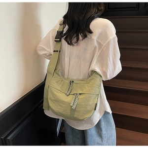 Detail of sage green nylon crescent bag with woven zipper pull and adjustable strap