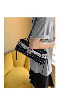Gros plan du sac à main noir à pois avec bordure en dentelle blanche et nœud rouge
