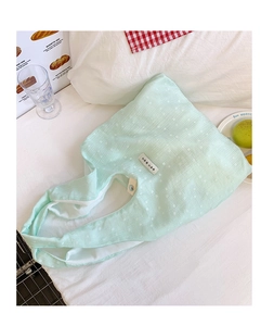 Detail of mint green floral canvas tote bag with textured fabric and vintage button detail