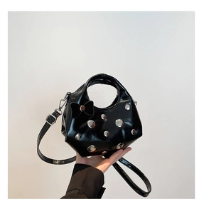 Detail of black patent leather crescent bag with silver studs and a velvet bow