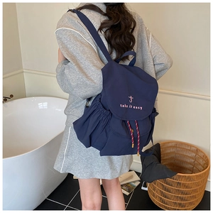 Détail du sac à dos en nylon bleu marine avec broderie et cordon de serrage tressé