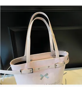 Détail du cabas en cuir verni rose avec nœud argenté et sangle à œillets métalliques