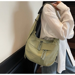 Detail of light green crescent nylon crossbody bag with adjustable wide strap and woven zippers