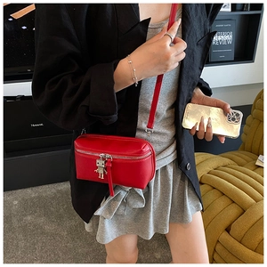 Close-up of red leather mini box bag with silver zipper and robot charm pendant