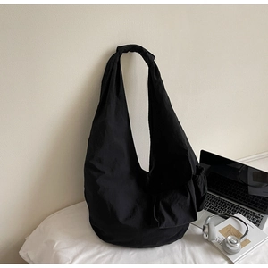 Detail of minimalist black oversized hobo bag with side drawstring and wide strap design