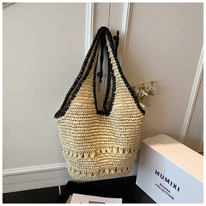 Detail of hand-woven straw shoulder bag with black contrast strap and hollow geometric pattern