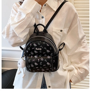 Detail of black mini floral backpack with purple butterfly prints and plush charm