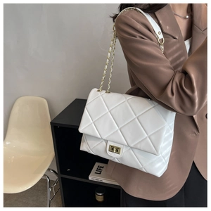 Detailed side view of a white quilted leather bag with gold chain and turn-lock closure