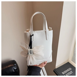 Detailed shot of white leather bucket bag with organza flower charm and fashion logo