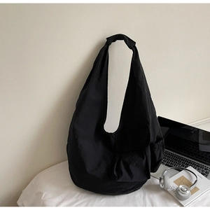 Detail of a black large-capacity canvas crossbody bag with decorative knotted shoulder strap