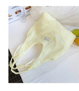 Detail of light yellow floral canvas tote bag with Korean label on a white bed
