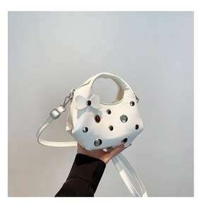 Detail of white matte crescent bag with silver studs and a decorative bow on the surface