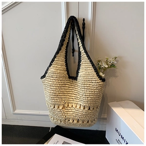 Straw tote bag with black trim hanging on a white door handle in a bright home setting