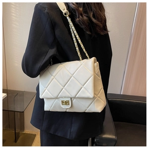 Detail of quilted diamond pattern and metallic square lock on the white chain shoulder bag