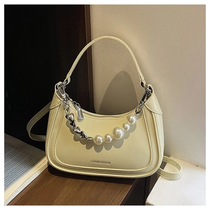 Detail view of cream leather dumpling bag with pearl and metal heart chain accent