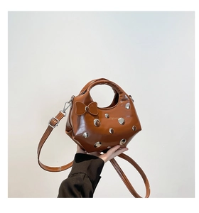 Detailed shot of brown semi-circle handbag with silver rivets and leather bow detail