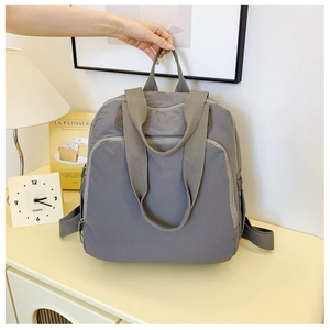 Detalle de mochila gris de nailon impermeable con cremallera oculta en un ambiente de hogar