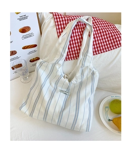Detail of blue striped canvas tote bag with shoulder strap on lifestyle background