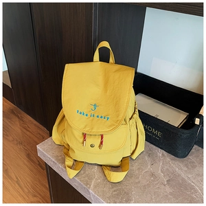 Détail d'un sac à dos en nylon jaune avec broderie Take It Easy et cordon de serrage