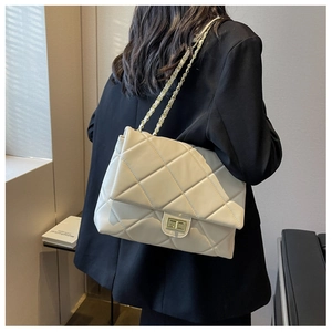 Detail shot of beige quilted crossbody bag with gold chain strap worn by a model