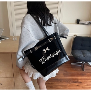 Détail d'un grand sac cabas en cuir verni noir avec imprimé nœud porté par un mannequin
