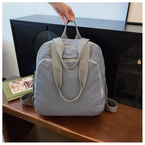 Detalle de mochila grande de nailon azul claro con asa ancha y cierre de cremallera