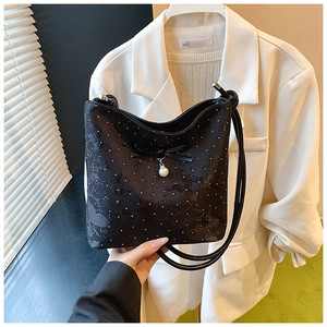 Detail of black polka dot bucket bag featuring a bow and white pearl pendant decoration