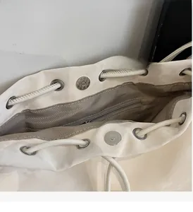 Detail of cream white backpack featuring drawstring closure, magnetic snap and herringbone lining