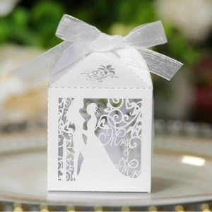 White laser-cut Mr & Mrs wedding favor box with ribbon on an elegant gold-edged plate