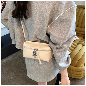 Detailed shot of cream mini crossbody bag featuring a robot charm and zipper detail