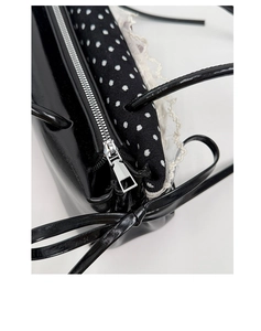 Détail du sac en cuir noir brillant avec bordure en dentelle blanche et doublure à pois