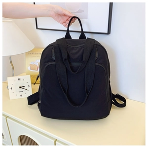 Primer plano de una mochila negra de nailon con compartimento grande y asas resistentes