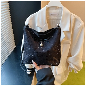 Detail of black bow shoulder bag with white polka dots and a decorative pearl pendant