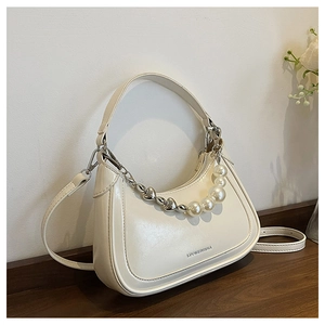Détail d'un sac hobo blanc cassé avec chaîne cœur et perles, arborant le logo de marque