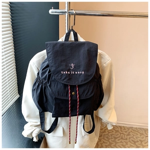 Détail d'un sac à dos en nylon noir avec broderie rose et cordons de serrage rouges