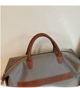 Gros plan des poignées en cuir marron et coutures solides sur le sac cabas en toile grise