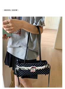 Sac à bandoulière à pois avec dentelle blanche et nœud en satin rouge porté par mannequin