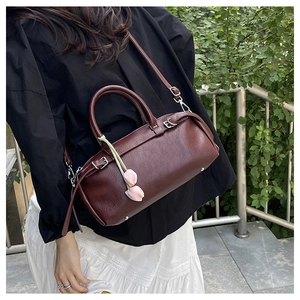 Detail of burgundy lychee leather bag with dual handles and pink tulip charm decoration