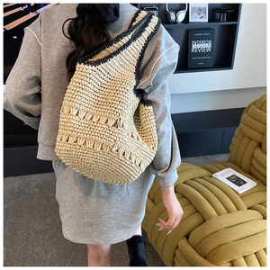 Detail of hollow-out woven design on large straw bucket bag with black trim and beige finish